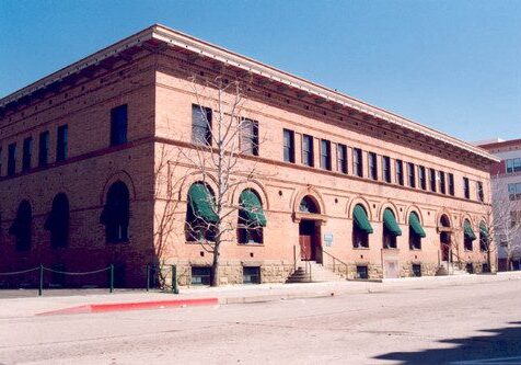 Historic brick building with green awnings on a sunny day.