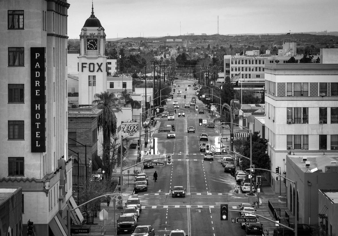 Busy city street with cars and buildings in black and white.